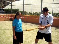 Un monitor enseñando a una alumna la técnica de golpeo con el bate de beisbol