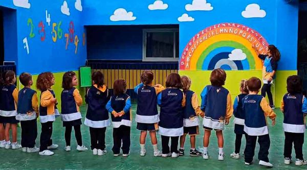 Chicos de primer ciclo de infantil alrededor de un arcoiris en la pared